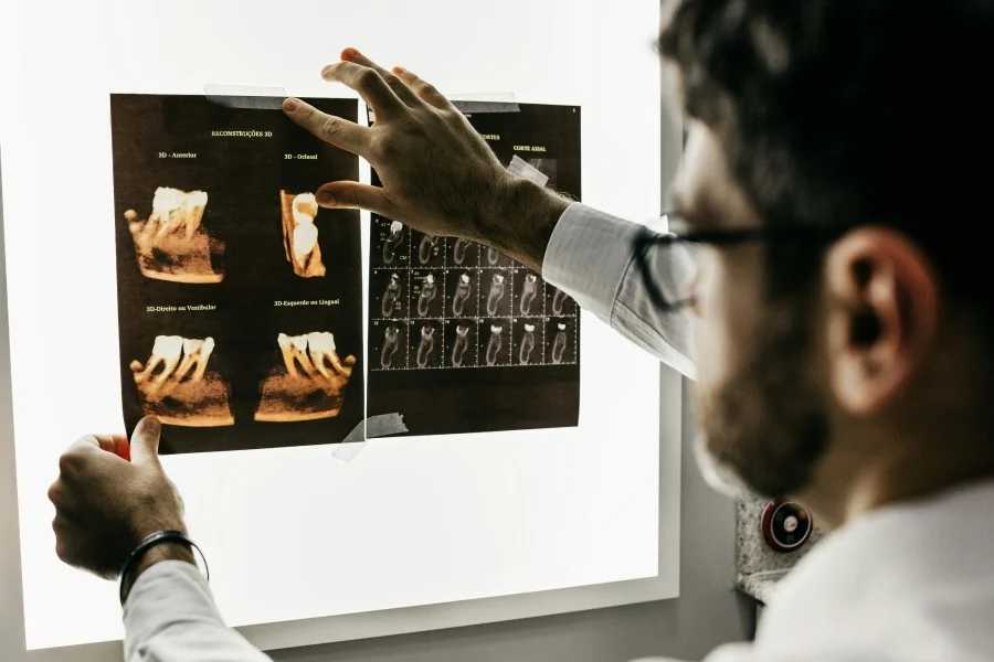 Dentist reviewing 3D dental scan and X-ray images to evaluate a patient's oral health and plan treatment in a modern dental clinic.