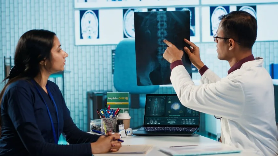 Dentist discussing a spinal X-ray with a patient in a medical office